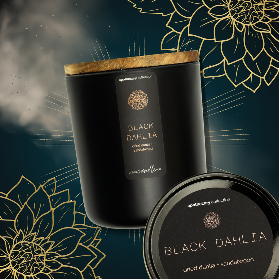 A dark teal background with gold sunbursts and dahlia flowers, with a Black Dahlia jar and tin over it. The black jar has a black rectangle label placed vertically on the jar which has copper lettering that says "Black Dahlia", copper dahlia graphic and scent notes that say "dried dahlia and sandalwood".
