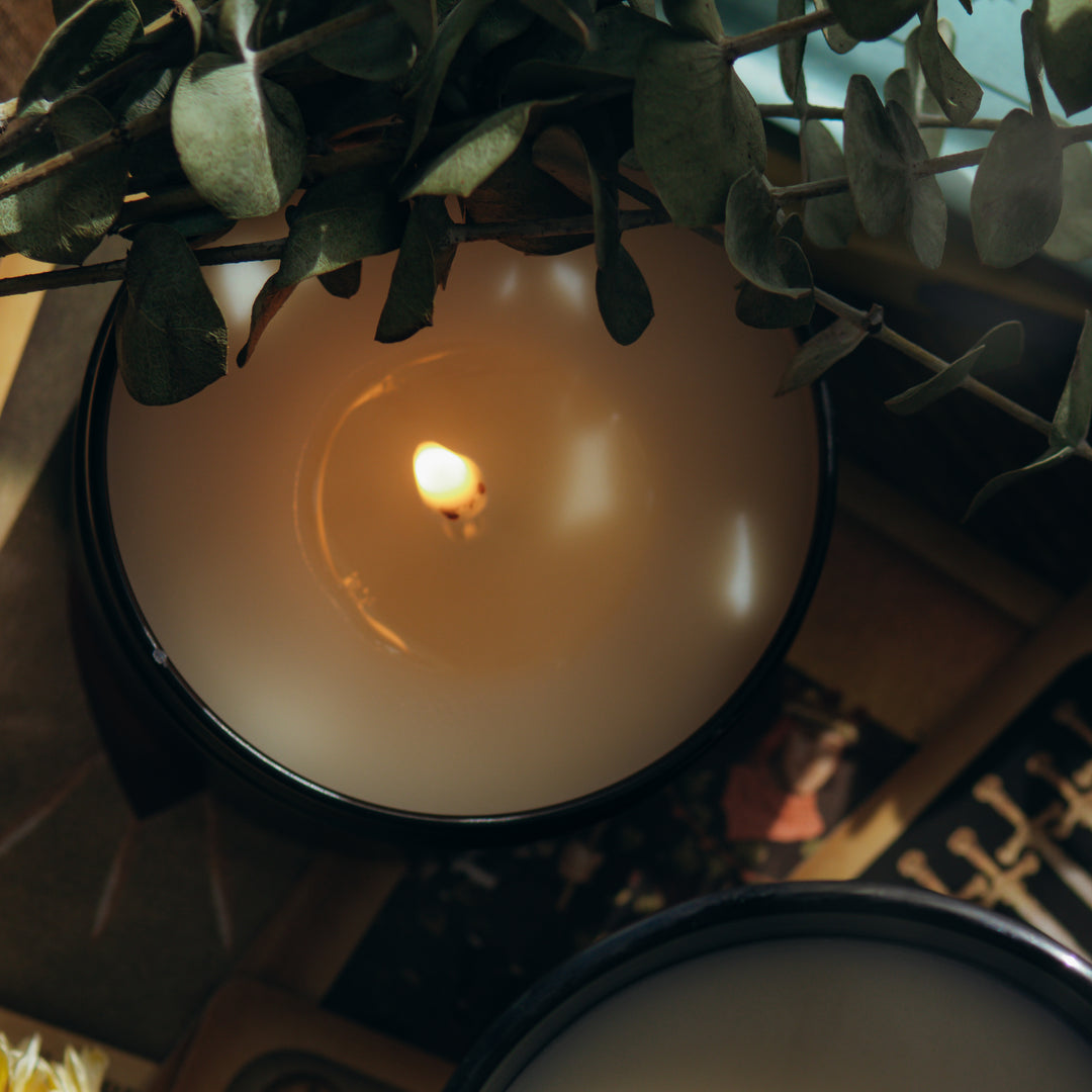 Shot from the top of the candle showing the lit  candle next to eucalyptus.